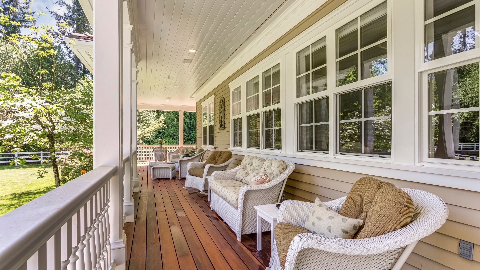 Cozy front porch with white wicker chairs and wooden deck overlooking trees