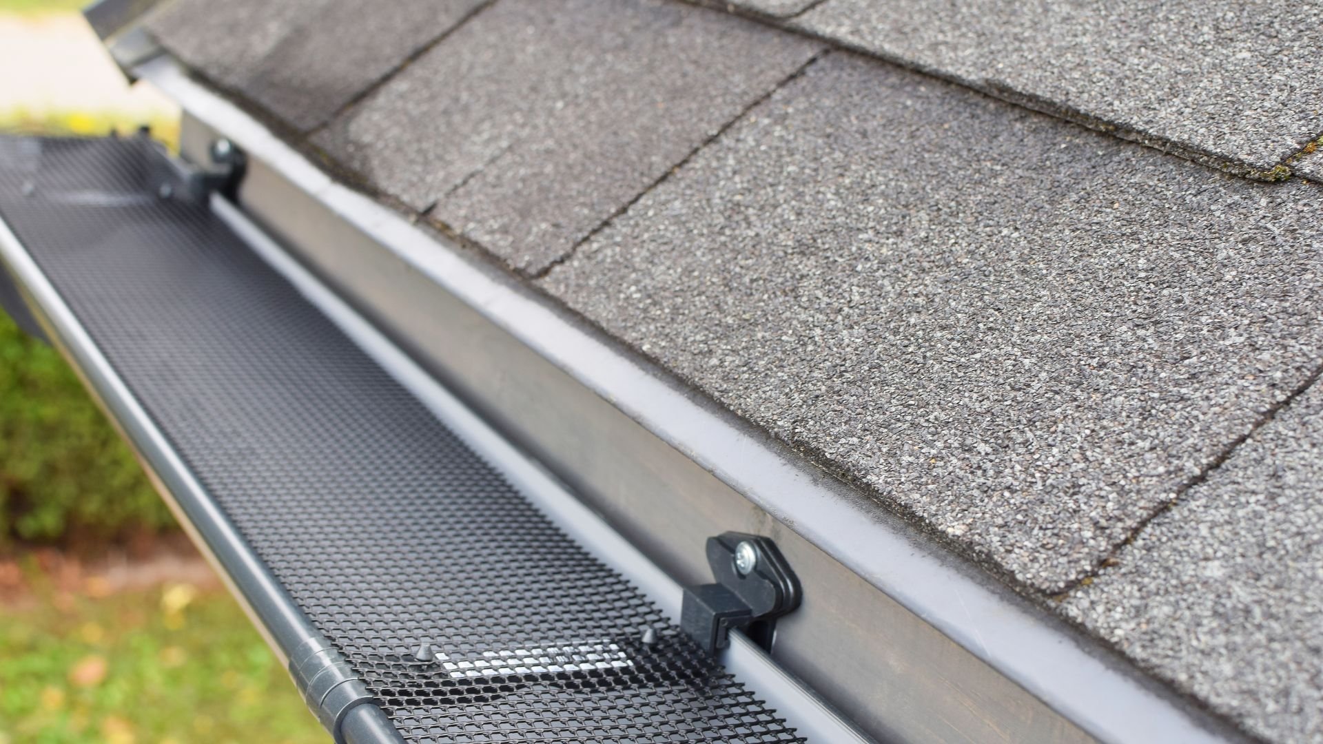 Gutter guard installed on roof with shingles, preventing debris buildup